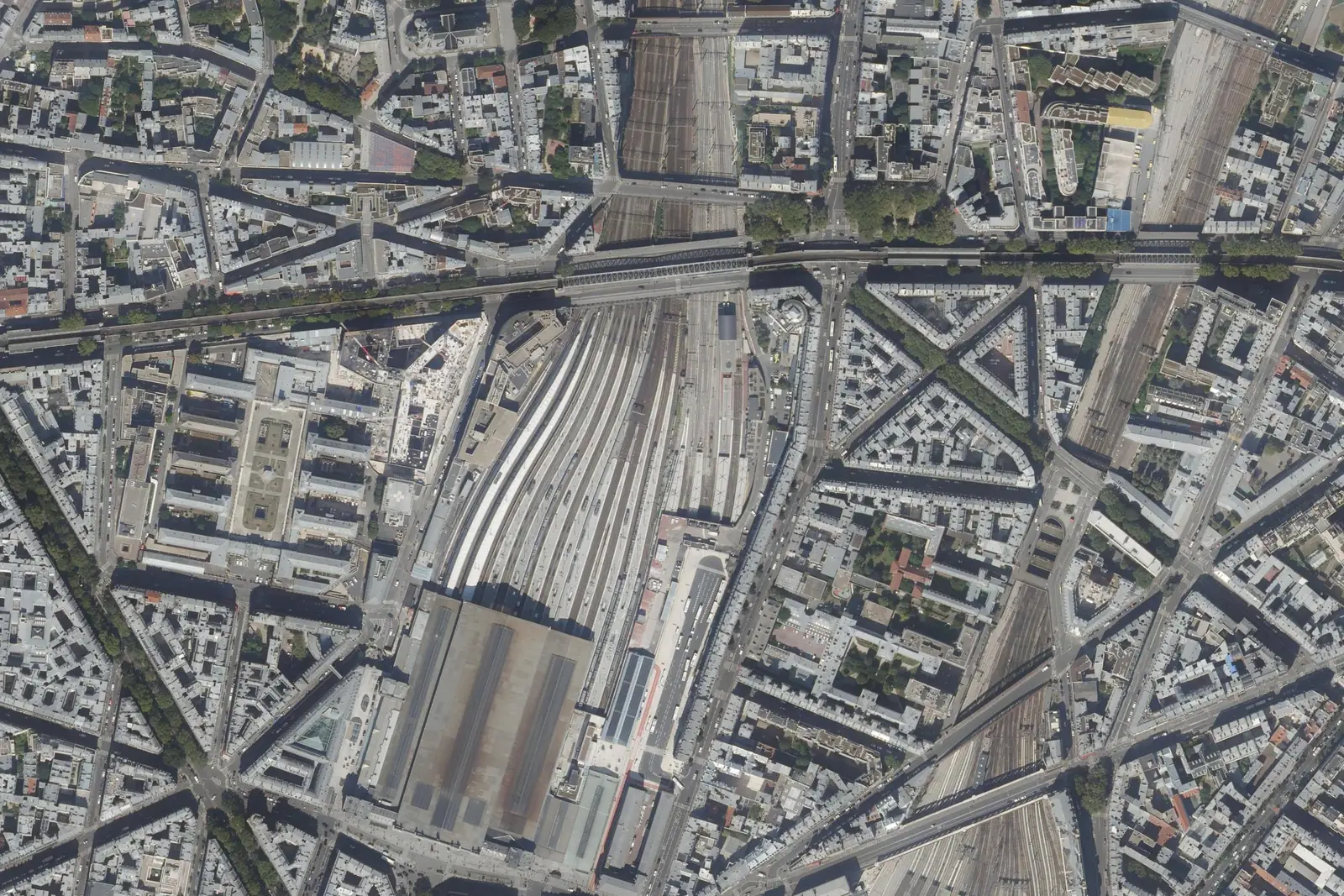 Vue aérienne de la gare du Nord à Paris : la grande halle, le faisceau de voies qui part vers le nord sous le boulevard de la Chapelle, et les immeubles qui le bordent