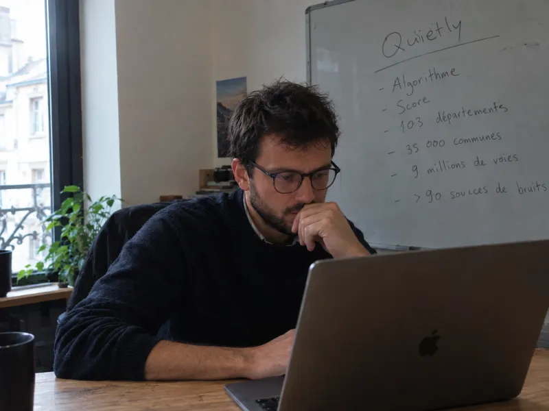 Thomas, ingénieur chez Quietly, au travail devant un tableau blanc qui présente Quietly