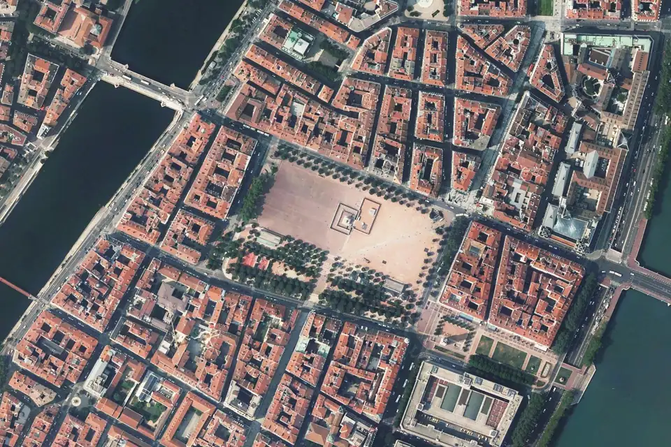 Vue aérienne de la place Bellecour à Lyon, entourée de toits de tuiles entre Rhône et Saône